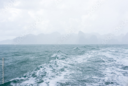 Fototapeta Naklejka Na Ścianę i Meble -  Waves and raindrops in sea with mountain and cloud