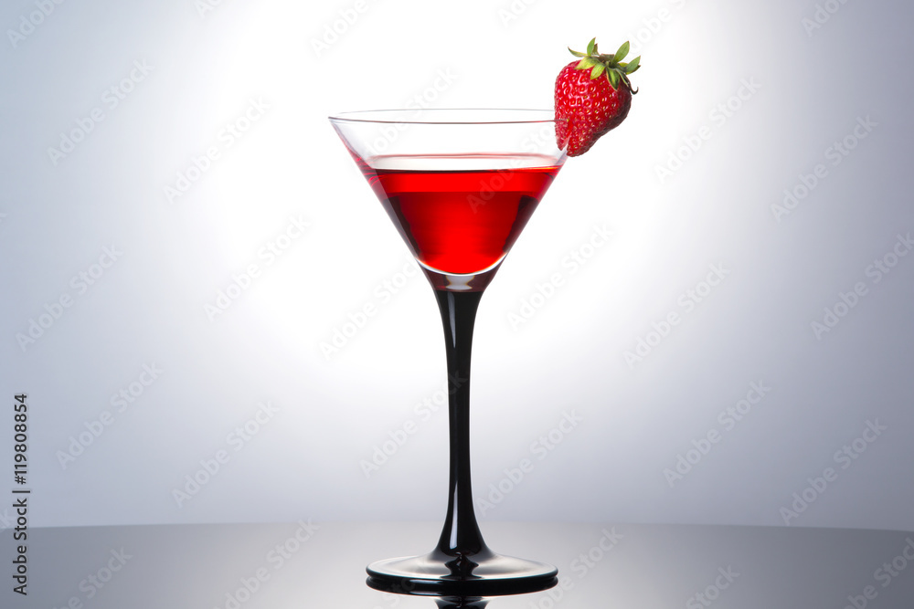 Red cocktail with liqueur and strawberry in martini glass