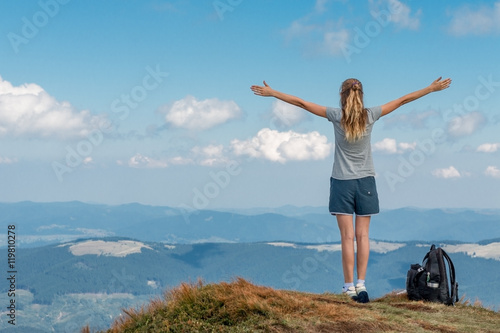 athletic girl climbed on top of the mountain and enjoys the freedom of hands opening