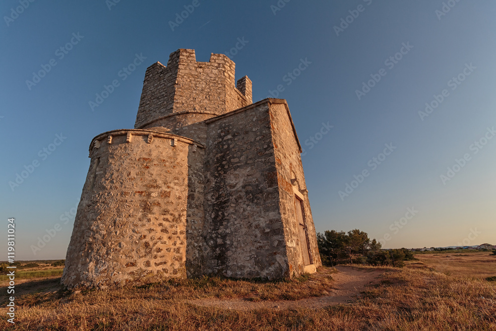 Old small stone church of St. Nicholas on hill near city of  Nin in Croatia. Golden hour.