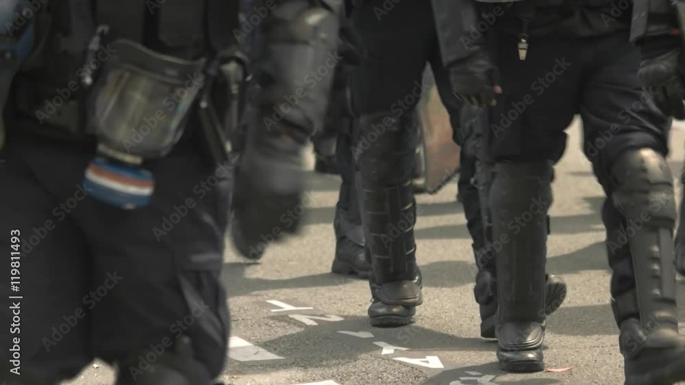 Squad of riot police. Policemen walk on road. Unrest in the city. Protect the peaceful citizens. Squad of riot police. Policemen walk on road. Unrest in the city. Protect the peaceful citizens.