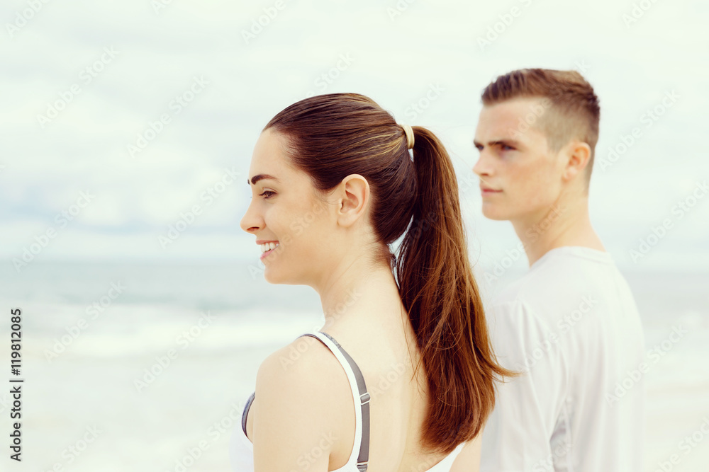 Young couple looking thoughtful while standing next to each other on beach Young couple looking thoughtful while standing next to each other on beach