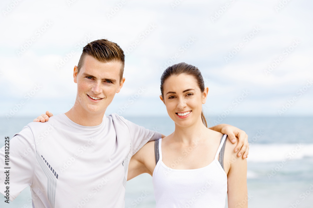 Young couple looking at camera while standing next to each other on beach Young couple looking at camera while standing next to each other on beach