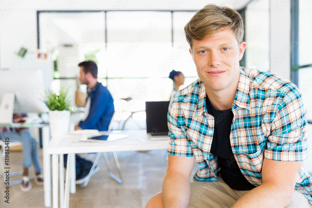 Fototapeta premium Young man sitting and looking at camera in office