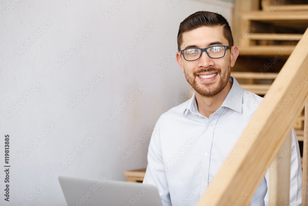 Fototapeta premium Portrait of young man sitting at the stairs in office