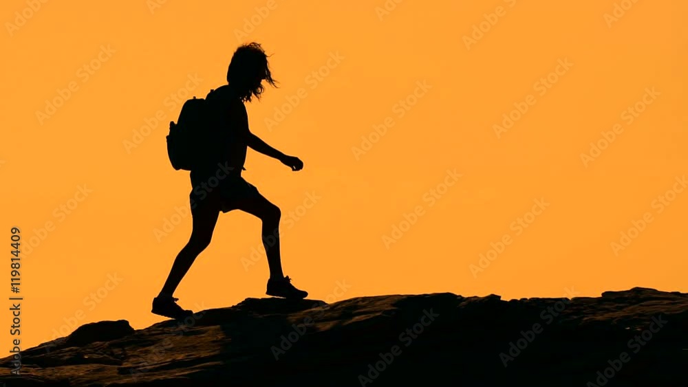 Silhouette of a girl walking on the mountain at sunset Silhouette of a girl walking on the mountain at sunset