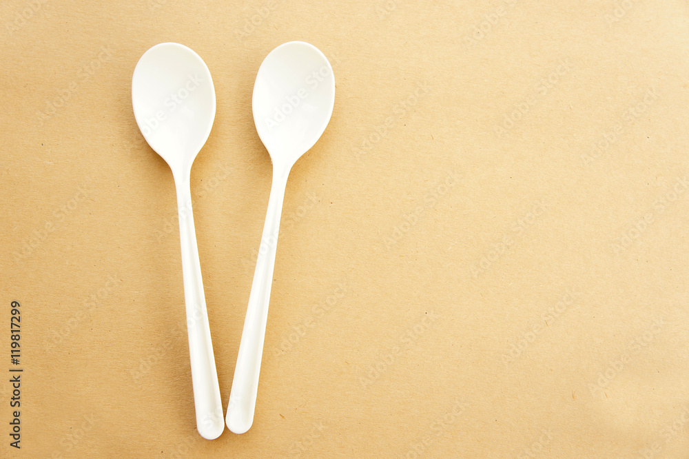 Twin spoons on brown background ,White spoon, The device is one of the cooking container. in eating Twin spoons on brown background ,White spoon, The device is one of the cooking container. in eating