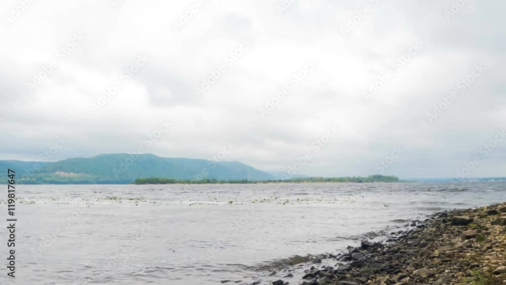 Waves on the shore of the river Volga, Russia. A storm in autumn day. The mountains and islands in the background. Windy weather. The clouds in the sky.Time Lapse. Waves on the shore of the river Volga, Russia. A storm in autumn day. The mountains and islands in the background. Windy weather. The clouds in the sky.Time Lapse.