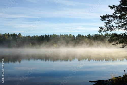 Beautiful lake view with early morning fog on lake surface, Finland.