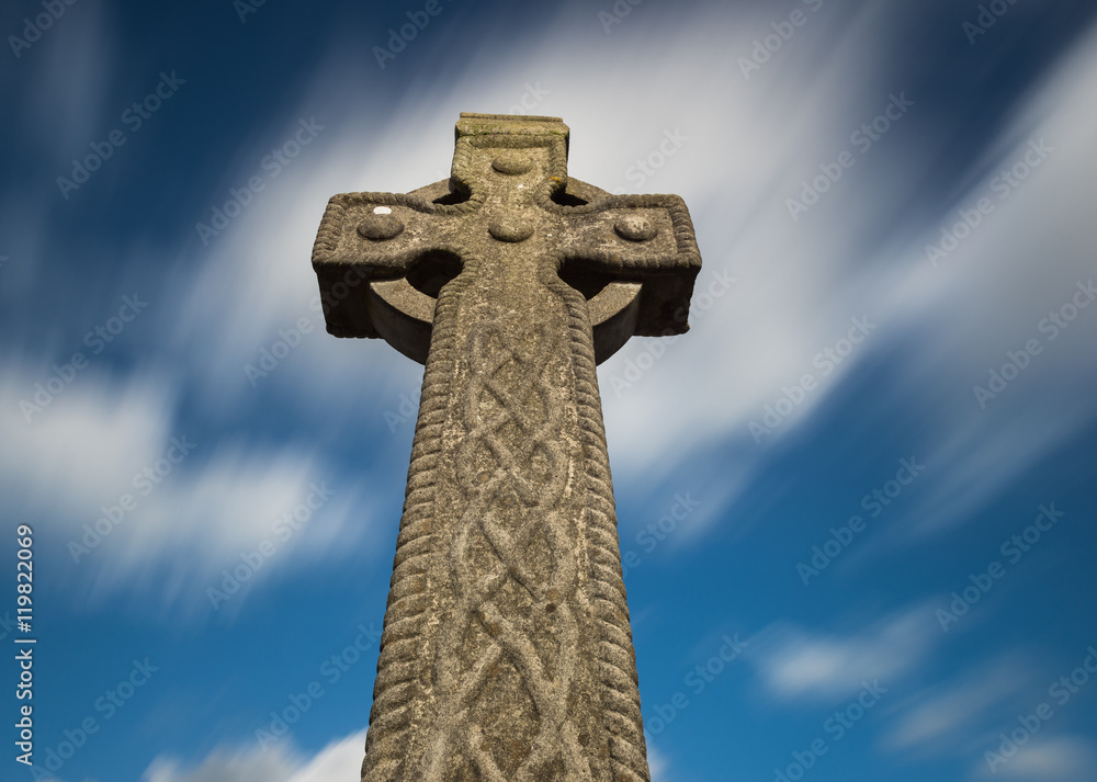Celtic cross gravestone with fast moving dramatic sky background