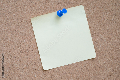 Yellow Sticker and Blue Pushpin with cork background.