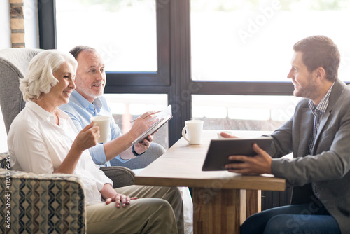 Cheerful sales manager talking with senior couple