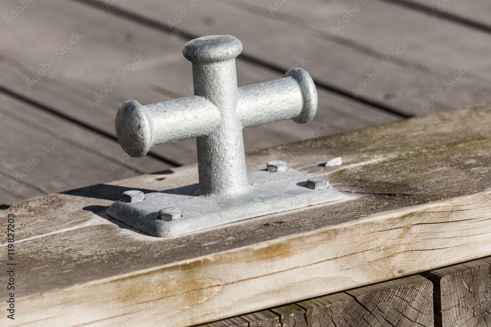 Small gray mooring bollard on wooden pier Small gray mooring bollard on wooden pier