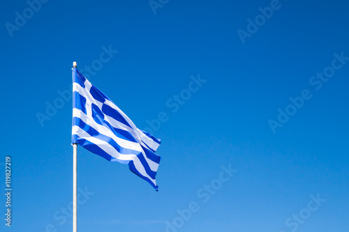 Flag of Greece waving on flagpole over blue sky