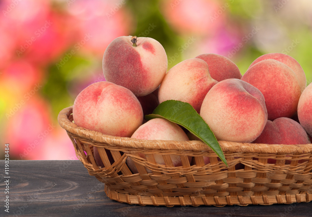 peaches in a wicker basket on wooden table with blurred background peaches in a wicker basket on wooden table with blurred background