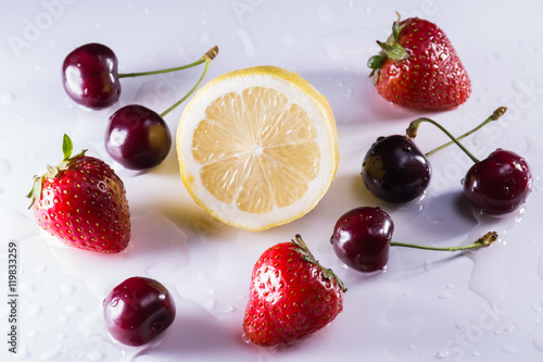 Fototapeta Naklejka Na Ścianę i Meble -  Washed lemon, cherries and strawberries with drops of water on w