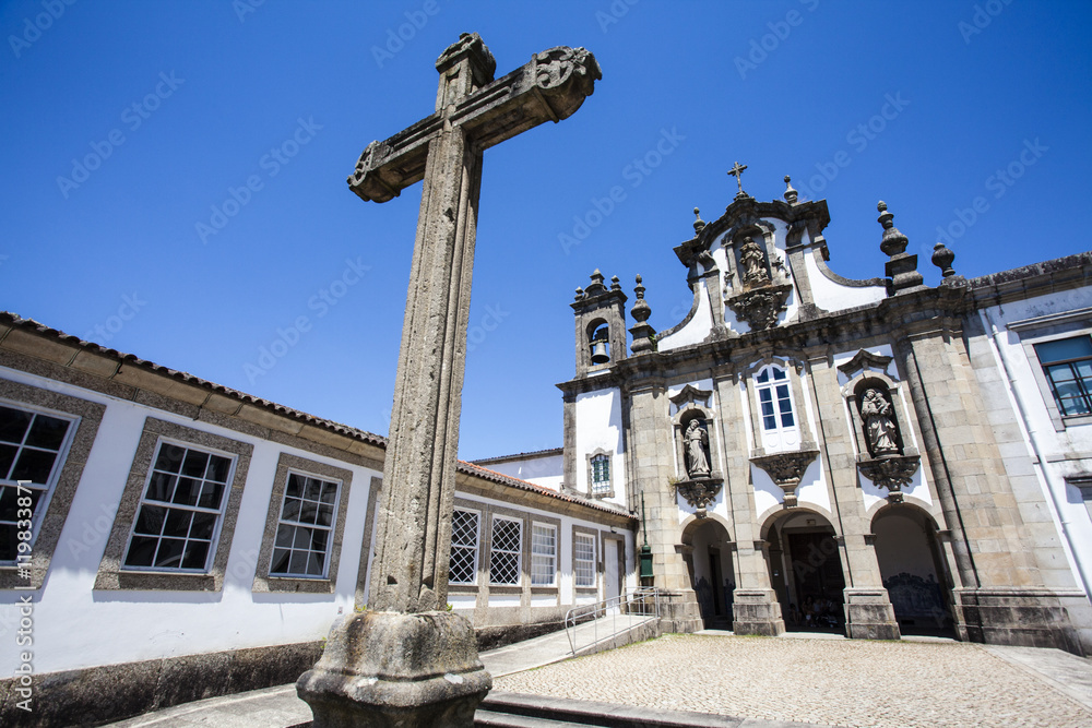 Facade of a Catholic church and a big stone cross in Guimaraes - Portugal - Europe