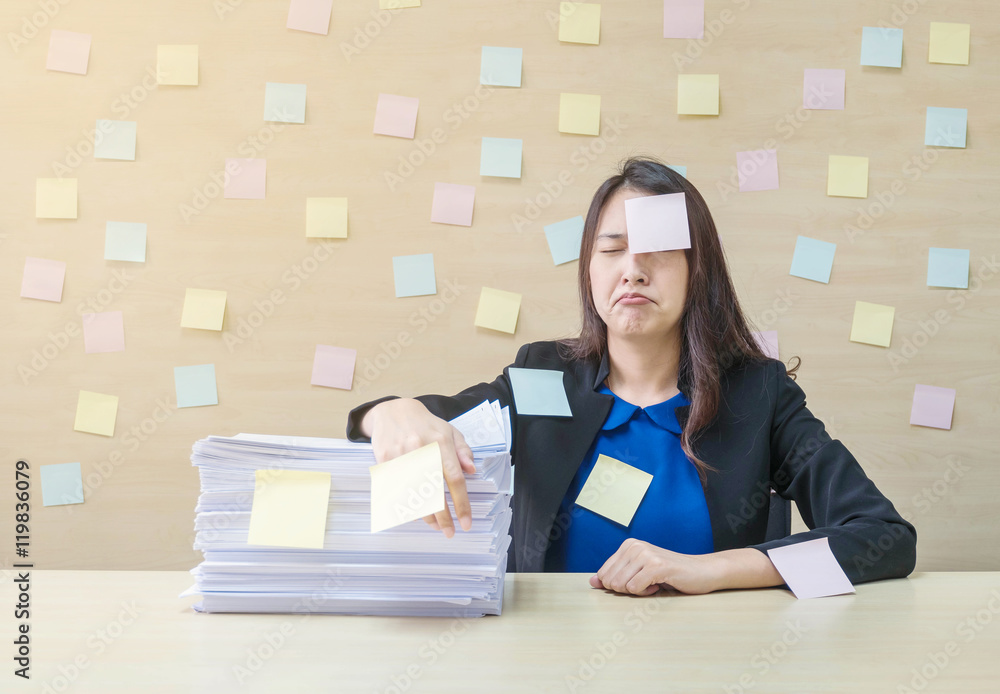 Closeup working woman are boring from pile of hard work and work paper in front of her in work concept on blurred wooden desk and wooden wall textured background in the meeting room Closeup working woman are boring from pile of hard work and work paper in front of her in work concept on blurred wooden desk and wooden wall textured background in the meeting room