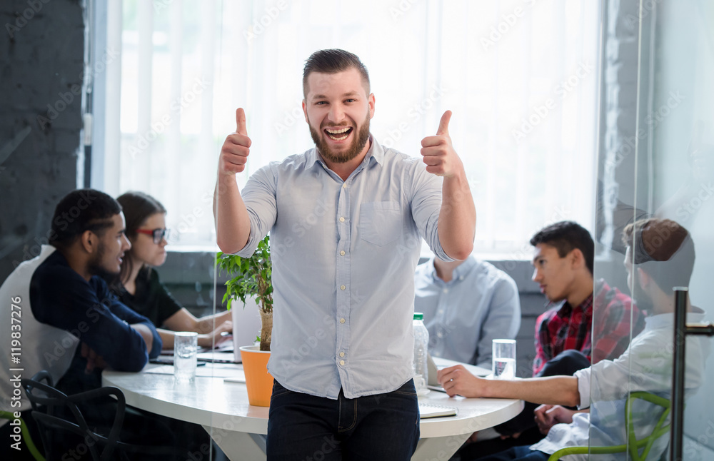 Picture of businessman showing thumb-ups while posing in office interior. Happy man showing victory of his company, enterprise or firm. Picture of businessman showing thumb-ups while posing in office interior. Happy man showing victory of his company, enterprise or firm.