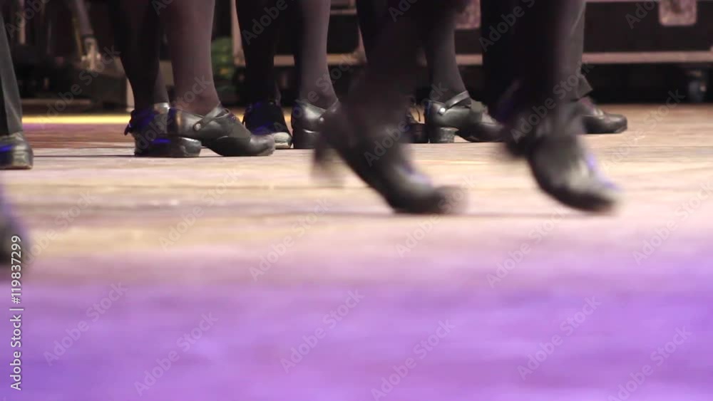 Two rows of women doing Irish dance with traditional step shoes. Close up double line people dancing feet on stage became one. Music, tradition and culture of Ireland. Celtic show on wooden floor Two rows of women doing Irish dance with traditional step shoes. Close up double line people dancing feet on stage became one. Music, tradition and culture of Ireland. Celtic show on wooden floor