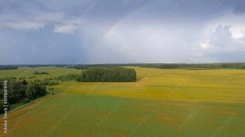 The sight of a rainbow from an aerial view of the cereal field on a fine weather The sight of a rainbow from an aerial view of the cereal field on a fine weather