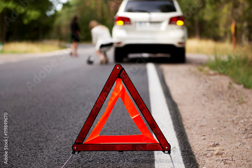 Red warning triangle and broken car in the middle of forrest