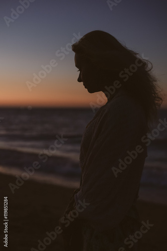 Silhouette of woman on the ocean beach. Natural summer beautiful sunset background