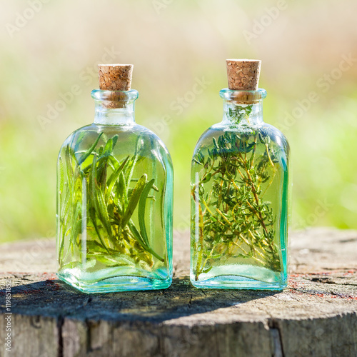 Bottles of thyme and rosemary essential oil or infusion outdoors