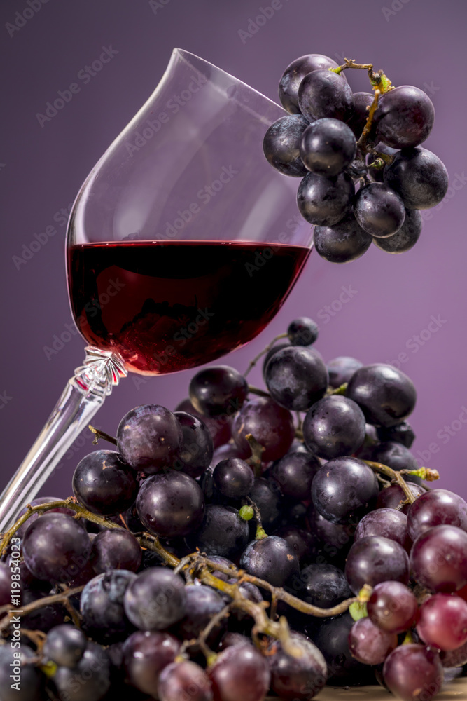 Glass of Rioja wine and red grapes, on purple background. Oenology