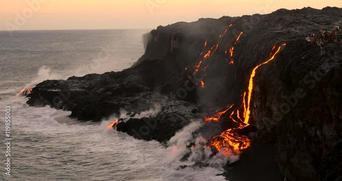 Tourist looking at Volcanic Eruption Lava flowing into the ocean. Steam rising from waves as molten lava flows into ocean waters Big Island Hawaii.