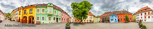 Panorama of the Sighisoara Citadel Square or Fortress Square, Romania. Colourful medieval houses with dramatic skies. Panoramic montage from 14 HDR images