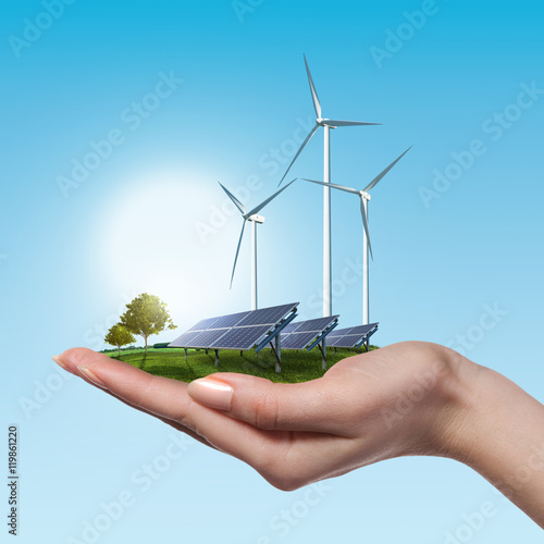 Wind turbines and solar panels in female hand