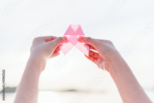 Healthcare and medicine concept - womans hands holding pink brea