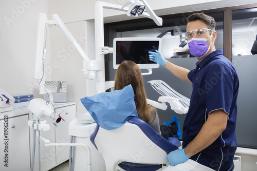 Portrait Of Dentist Showing Blank Screen To Female Patient