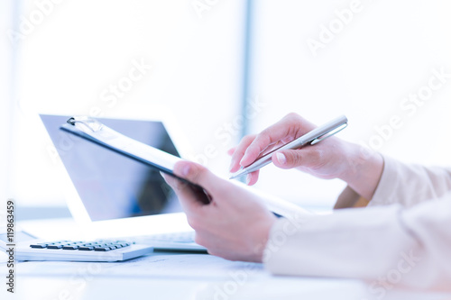 Photo of human hands holding pen and marking numbers in document photo