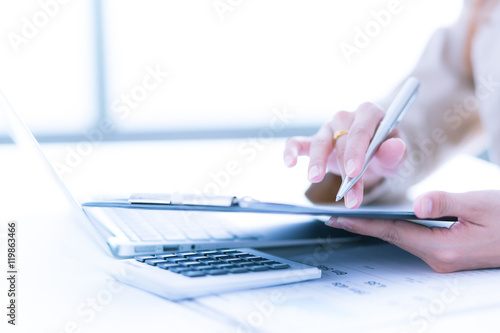 Photo of human hands holding pen and marking numbers in document photo