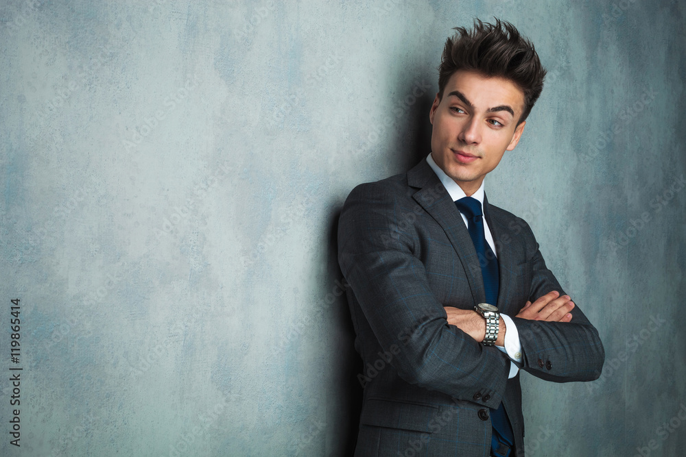 businessman standing against wall with hands crossed and looks a businessman standing against wall with hands crossed and looks a
