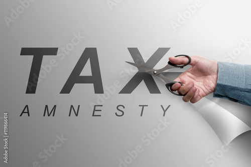 Fotografie The hand cutting the paper that reads tax amnesty