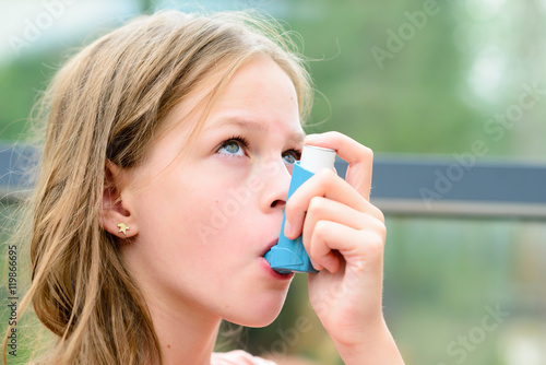 Girl uses an inhaler during an asthma attack photo