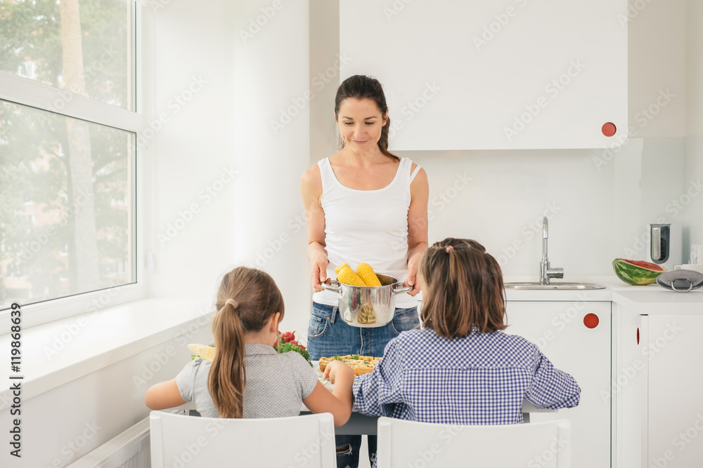 Young mother cooking tasty corn for children