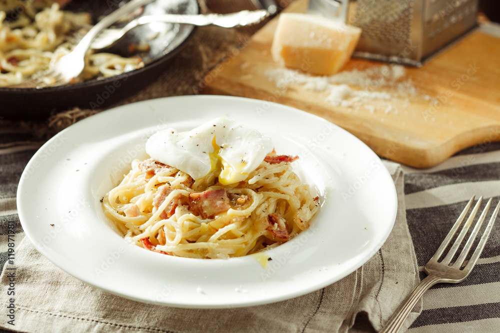 Plate of delicious spaghetti Carbonara with poached egg. Italian food. Rustic styled