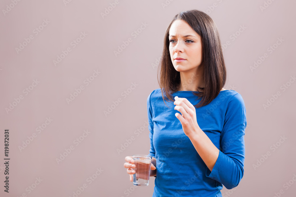 Portrait of young woman who is taking a pill because of illness. Portrait of young woman who is taking a pill because of illness.