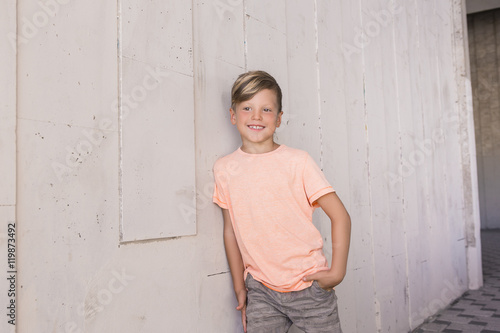 Fényképezés Stylish boy leaned on the wall and looks ahead with a smile