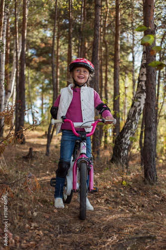 little girl riding in the protection of the forest cycling summer day.