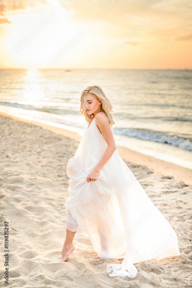 Beautiful stylish girl posing in sunlight on the beach Beautiful stylish girl posing in sunlight on the beach
