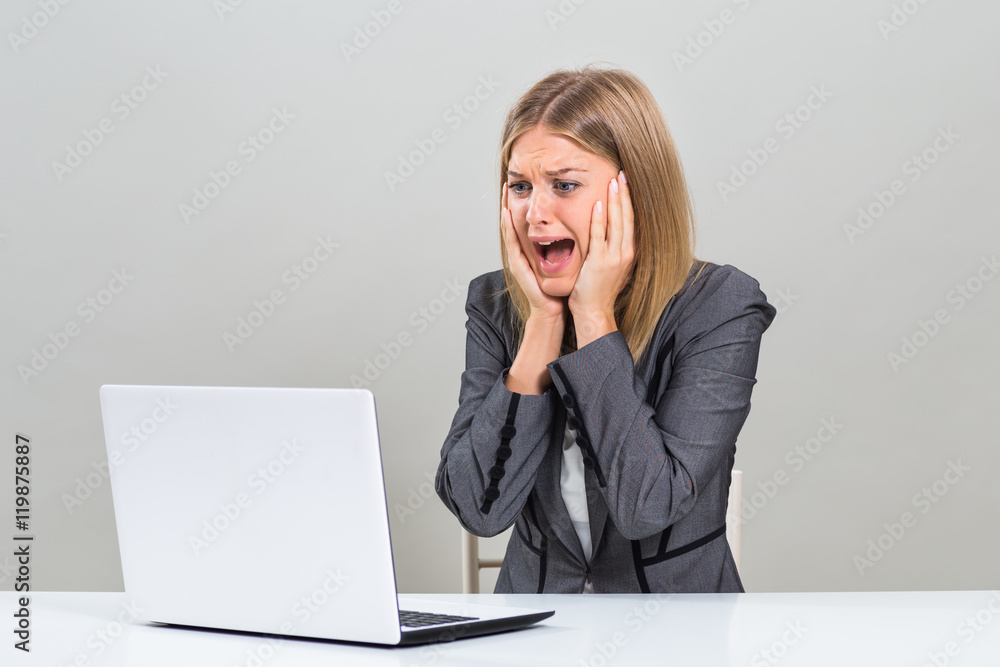 Businesswoman sitting at the table and looking at her laptop in panic.
Businesswoman sitting at the table and looking at her laptop in panic.