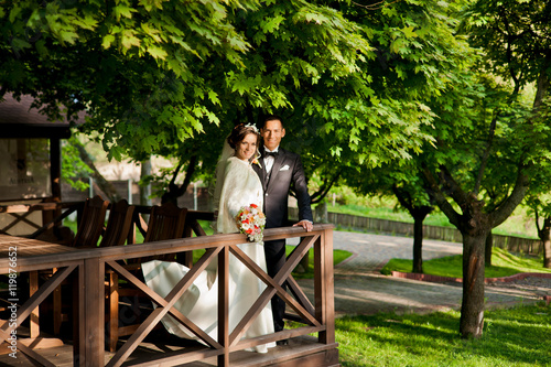 lovely wedding couple is standing on wooden balcony