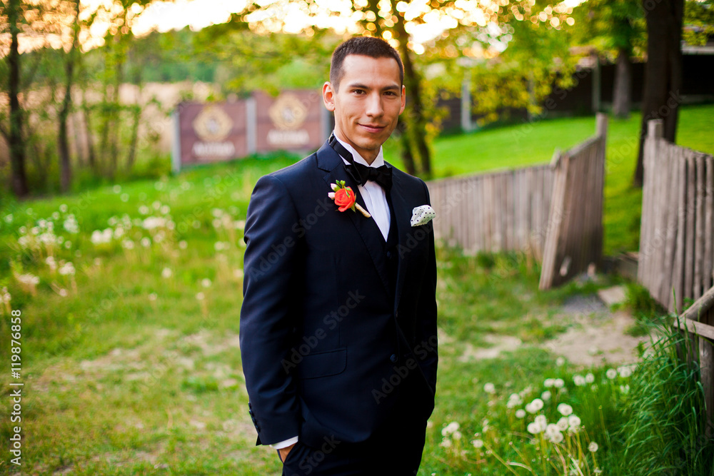 Handsome groom is standing and posing outside Handsome groom is standing and posing outside