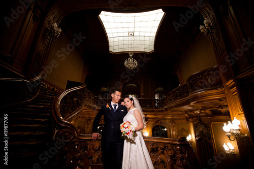 Cute wedding couple is standing and posing in old hall