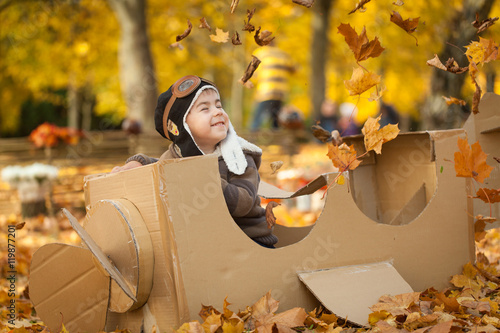 Fotografija Young boy in autumn park in a pasteboard airplane